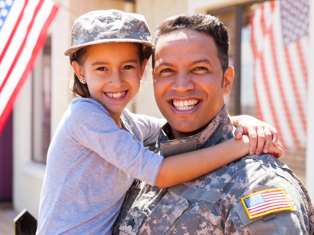 military serviceman smiling holding daughter