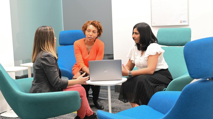 three diverse females sitting with computer and conversing